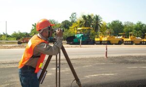 Construction surveyor using equipment to check ground levels at a road construction site