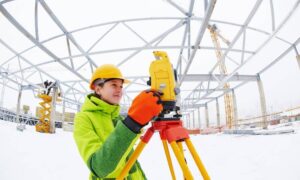 Winter site survey - ALTA SURVEY New York Licensed land surveyor using a total station at a snowy construction site to check property elevations after a freeze