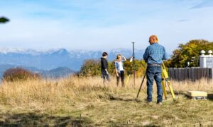 Surveyor measuring uneven ground elevation in the field as part of preparing a topo survey