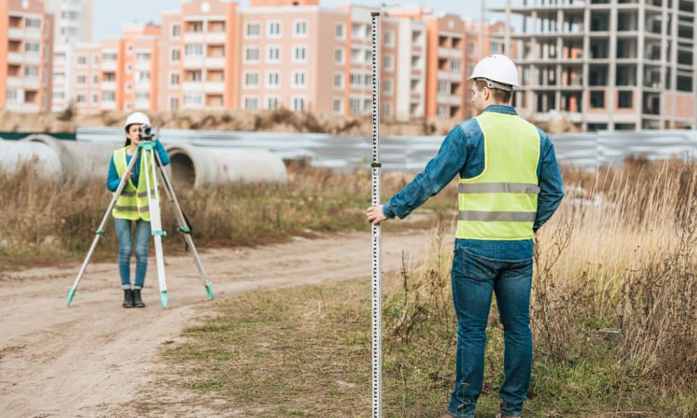 Surveyors using measuring equipment to perform a boundary line survey at a neighborhood redevelopment site