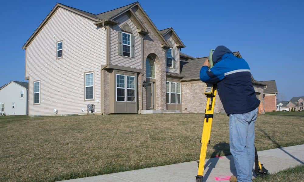 Licensed land surveyor measuring a residential property boundary