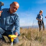 Boundary survey after natural disaster - ALTA SURVEY New York Licensed surveyor marking property boundaries with specialized equipment in an open field, demonstrating the boundary survey process after a natural disaster.