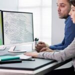City planners reviewing topographic survey maps and land development plans on computer screens to speed up permit approvals

