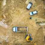 Drone surveying aerial view construction site - ALTA SURVEY New York Aerial view of a construction site showing trucks and heavy machinery, illustrating drone surveying in action.