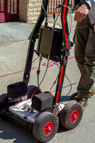 Ground penetrating radar construction survey - ALTA SURVEY New York Technician using ground-penetrating radar equipment to detect underground utilities and voids at a construction site