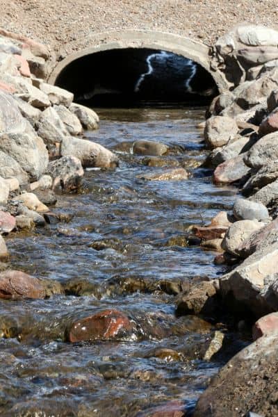 Drainage slope water flow culvert survey - ALTA SURVEY New York Water flowing through a drainage culvert showing how small elevation changes affect property runoff after a freeze