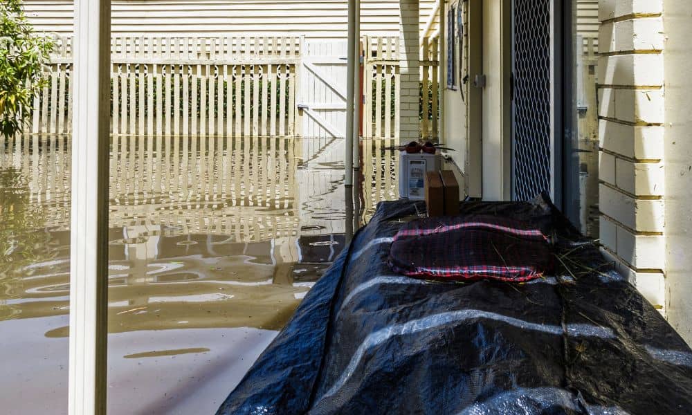 Flooded residential backyard showing standing rainwater near a house, illustrating why homeowners need a flood elevation survey
