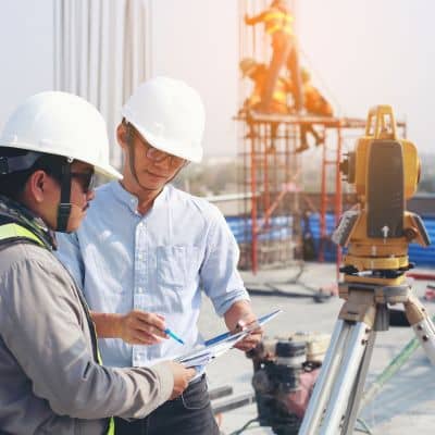 Surveyors reviewing plans on a commercial construction site during land survey verification