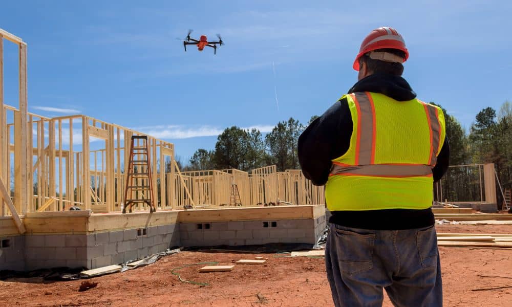 A surveyor operating a drone over a construction site to capture aerial surveying data