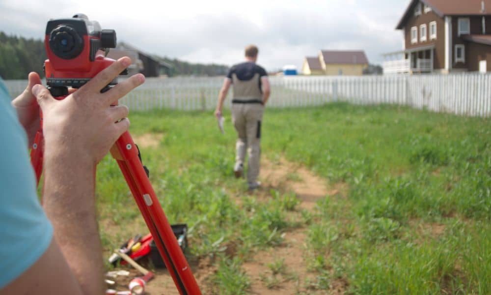 Licensed land surveyor measuring the elevation of a property for accurate flood risk assessment