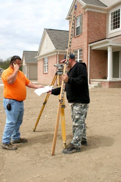 Two surveyors using professional equipment to measure property elevation for accurate FEMA documentation