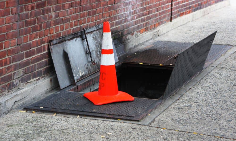 Open sidewalk vault hatch showing the underground space documented during an ALTA title survey