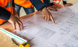 Surveyors and project professionals reviewing a property survey and building plans